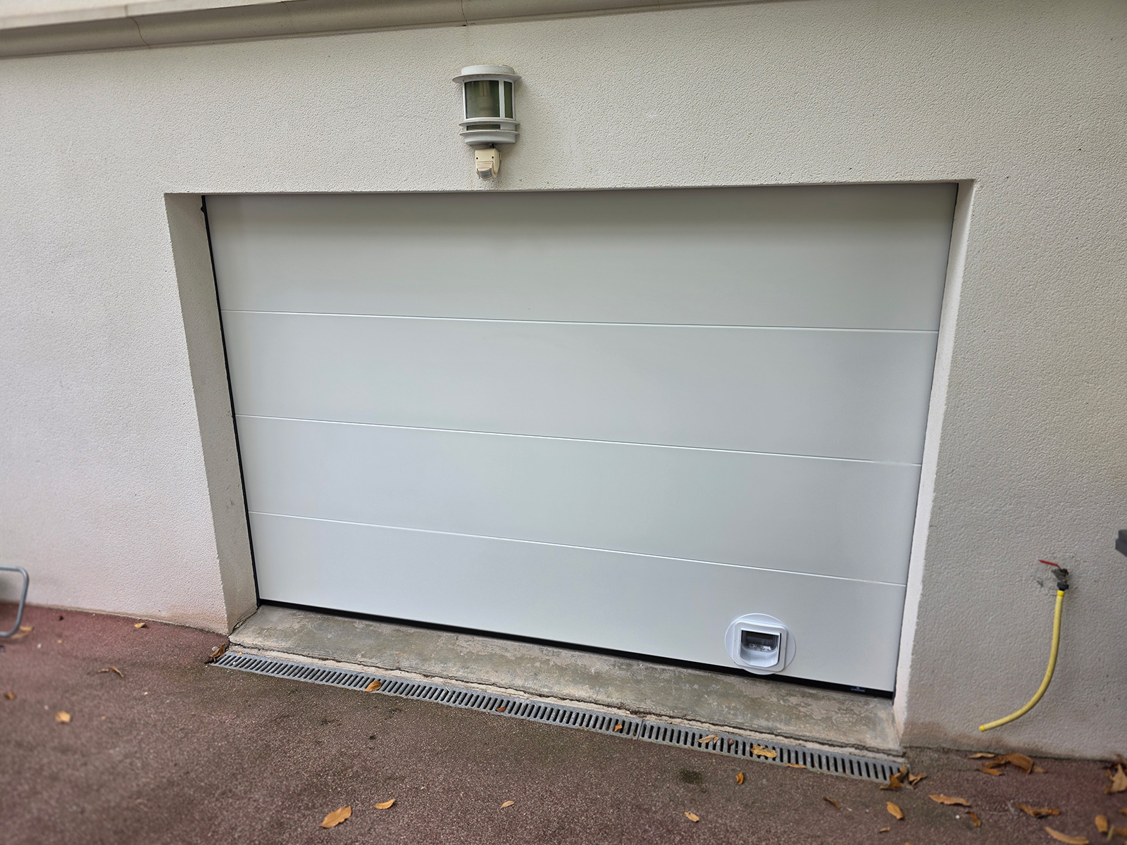 Porte de garage sectionnelle La Toulousaine à panneaux lisses sans nervures avec intégration d'une chatière