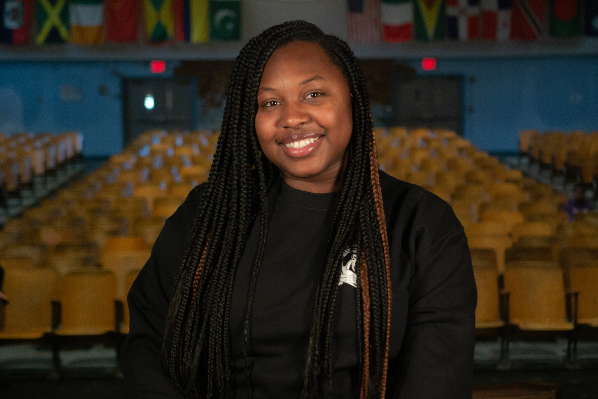 Smiling student in school auditorium with international flags displayed