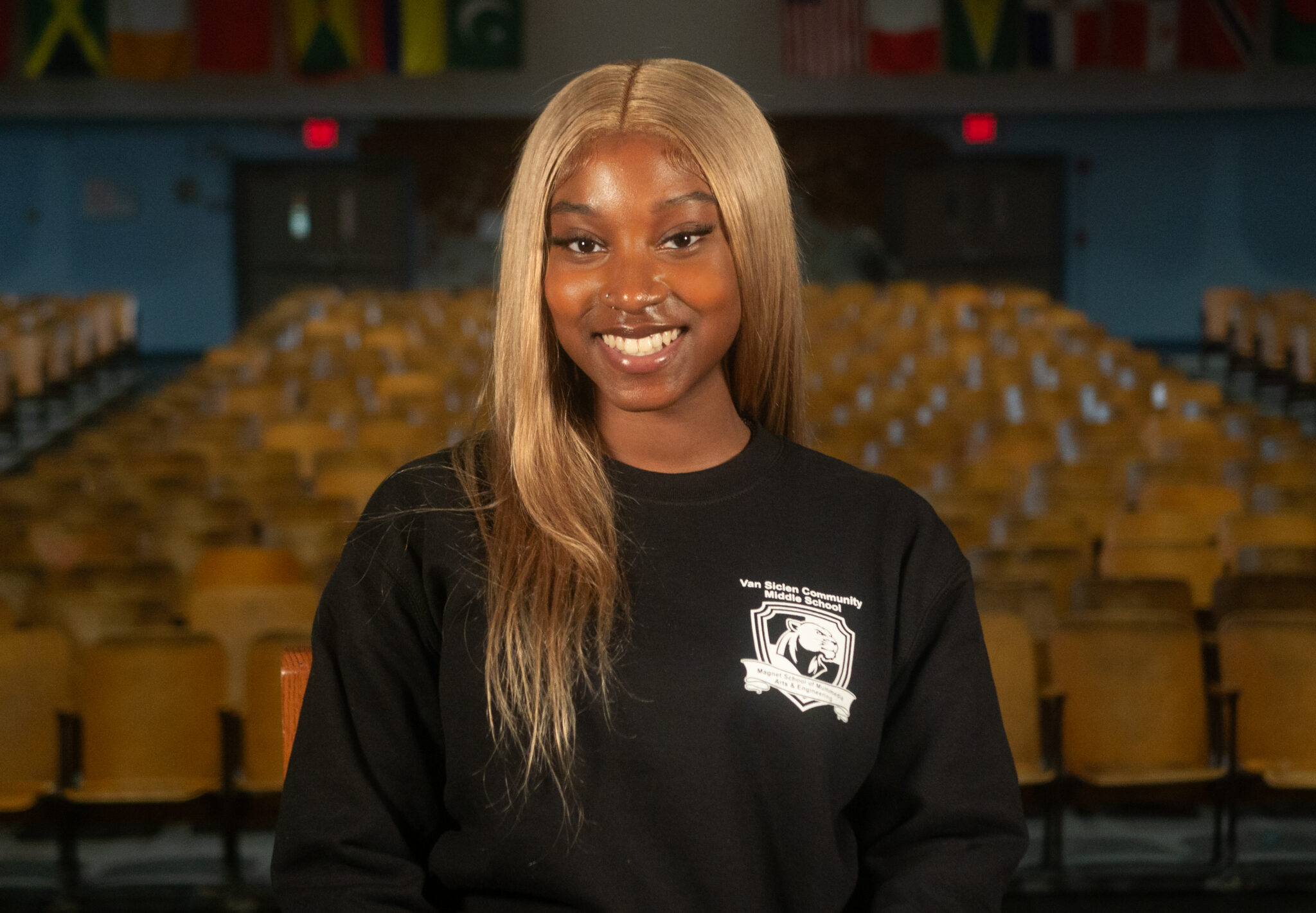 Student smiling in Van Siclen Community Middle School sweatshirt in auditorium