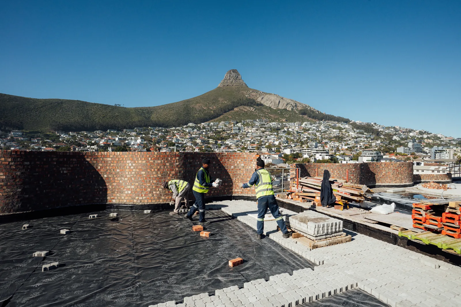 The R+N team laying brick paving on the Mont Reve roof with Lion's Head behind