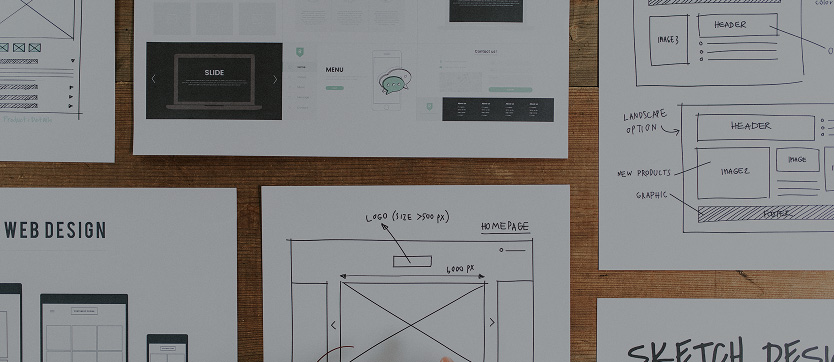Feuilles éparpillées sur une table, arborant des schémas de design system et de zoning, illustrant la phase de conception d’un site web. Cette image souligne l’importance de la documentation, de la structuration des composants et de la réflexion sur l’ergonomie et la hiérarchie visuelle, essentiels pour bâtir une interface homogène et évolutive.