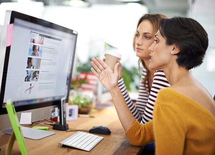 Deux personnes échangent devant un ordinateur affichant une page web, symbolisant la collaboration dans la conception de sites. L’image souligne l’importance du travail d’équipe et de l’écoute des besoins utilisateurs pour créer des interfaces web efficaces et ergonomiques.