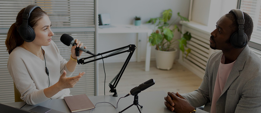 Enregistrement d’un podcast en studio : deux personnes équipées de casques et de microphones professionnels échangent autour d’une table. L’environnement moderne et lumineux met en avant la qualité du matériel audio et le savoir-faire en production sonore, idéal pour la création de podcasts, d’interviews ou de contenus audio professionnels.