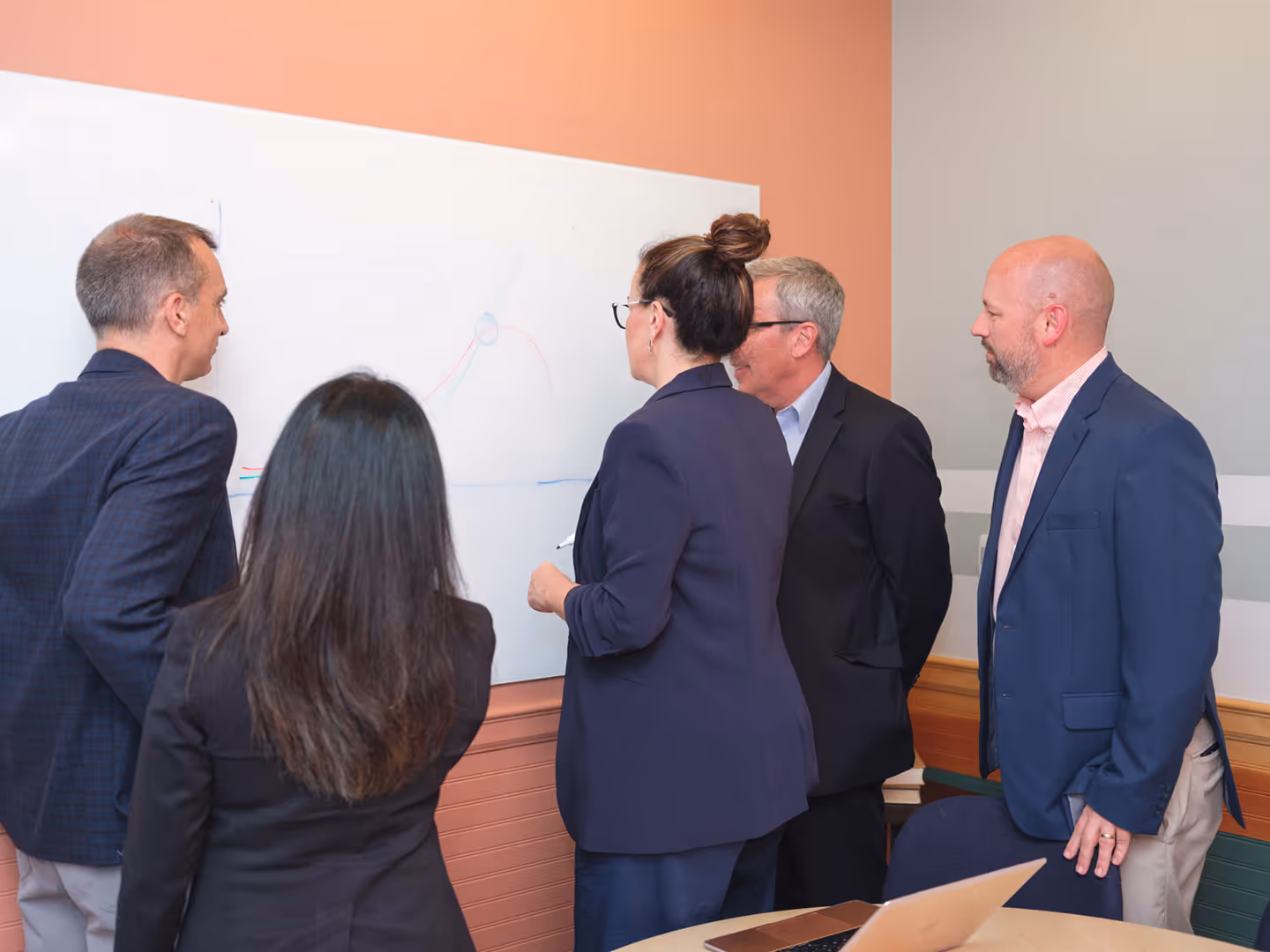 Business team gathered around a whiteboard discussing ideas during a strategy meeting.