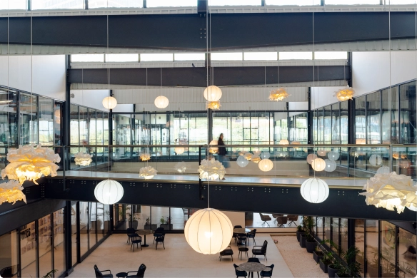 DevX Gift City modern two-story indoor space with round hanging lights and glass partitions enclosing tables and chairs.