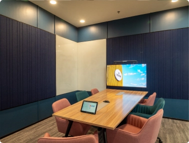 DevX Gift City modern conference room with wooden table, six chairs, and a screen displaying a sky image.
