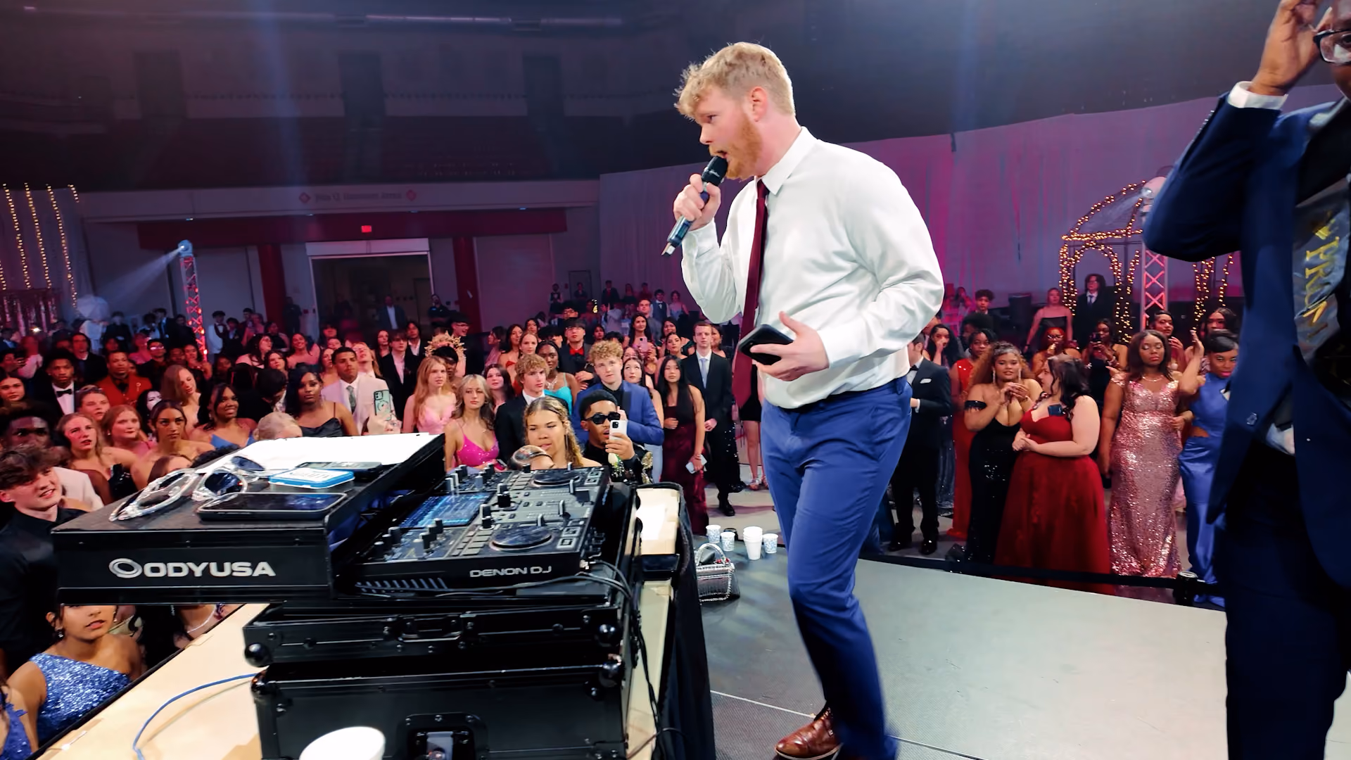 A DJ MCing on a stage at a school dance to get the crowd involved. 