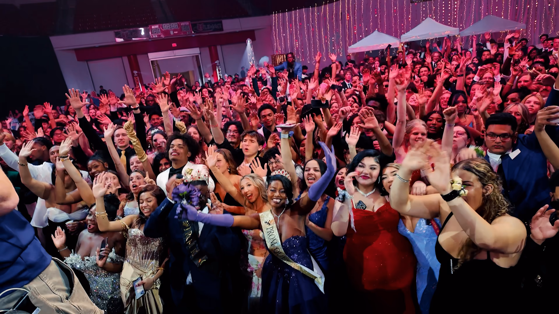 A point of view from a room full of students dancing with their hands in the air the DJ's songs.
