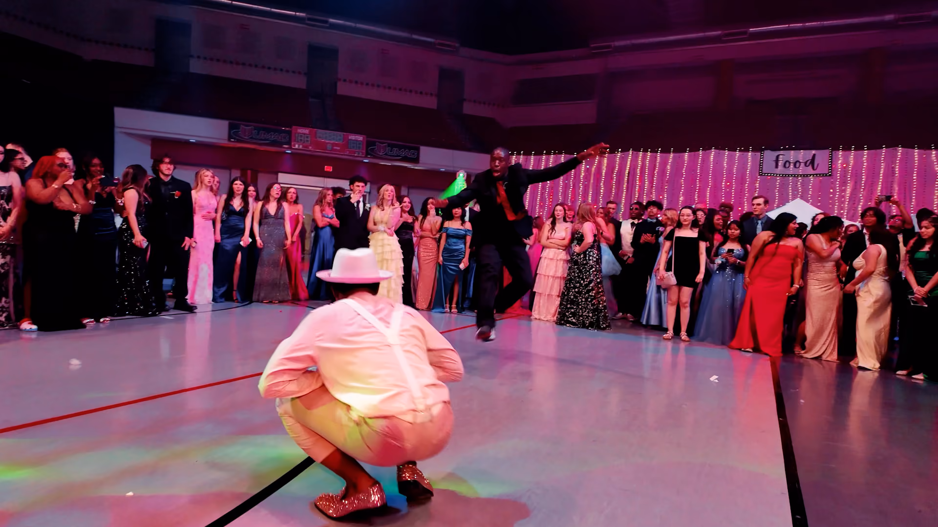 A group of students at prom gathered in a circle with two students dancing in the middle.