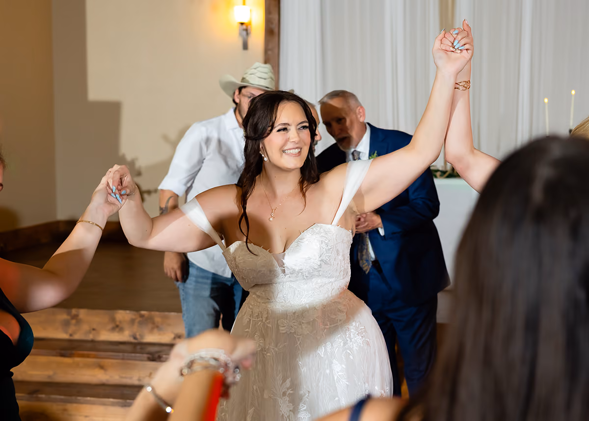 A smiling, happy bride in her wedding dress dancing with her guests. 