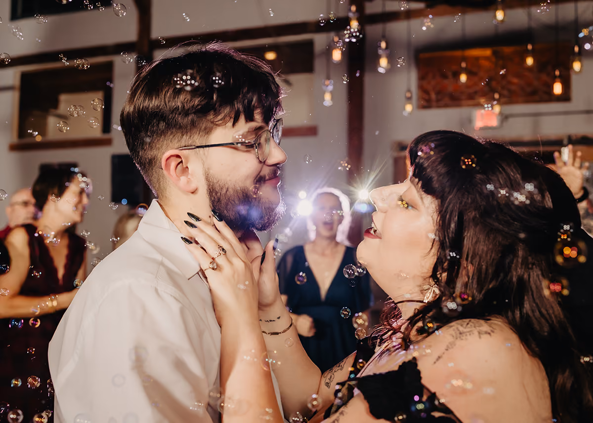 A newly married couple sharing a slow dance with bubbles floating in the air. 