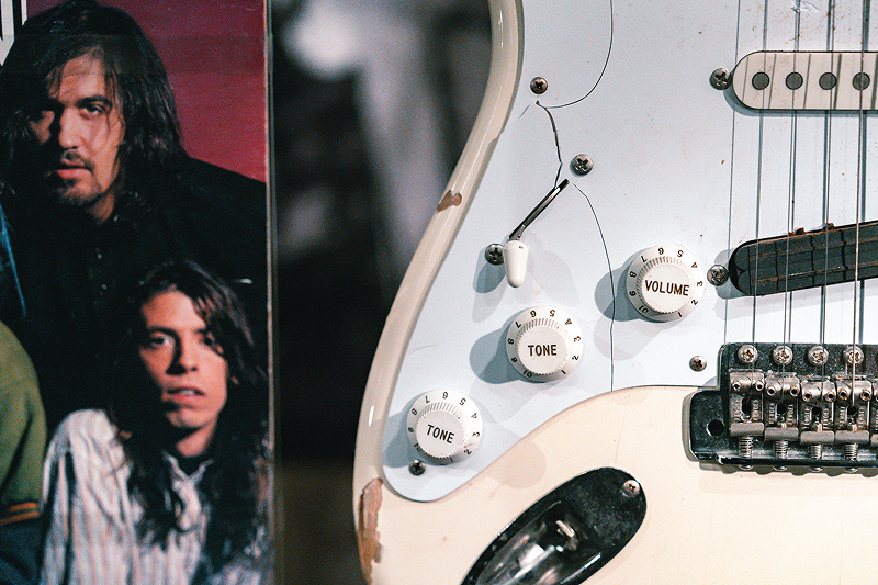 Split photo of band members and white guitar close up