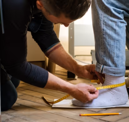 A man measuring a pair of socks with a tape.