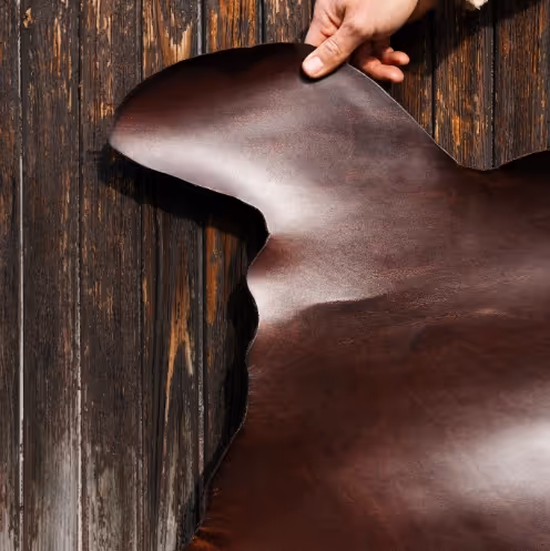 A person holding a piece of brown leather.