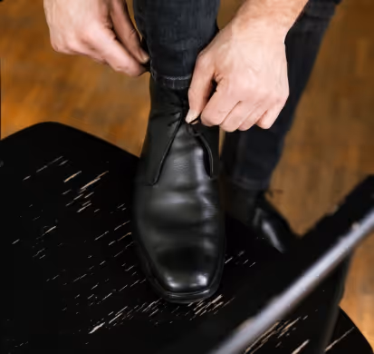 A person tying a shoelace on top of a chair.