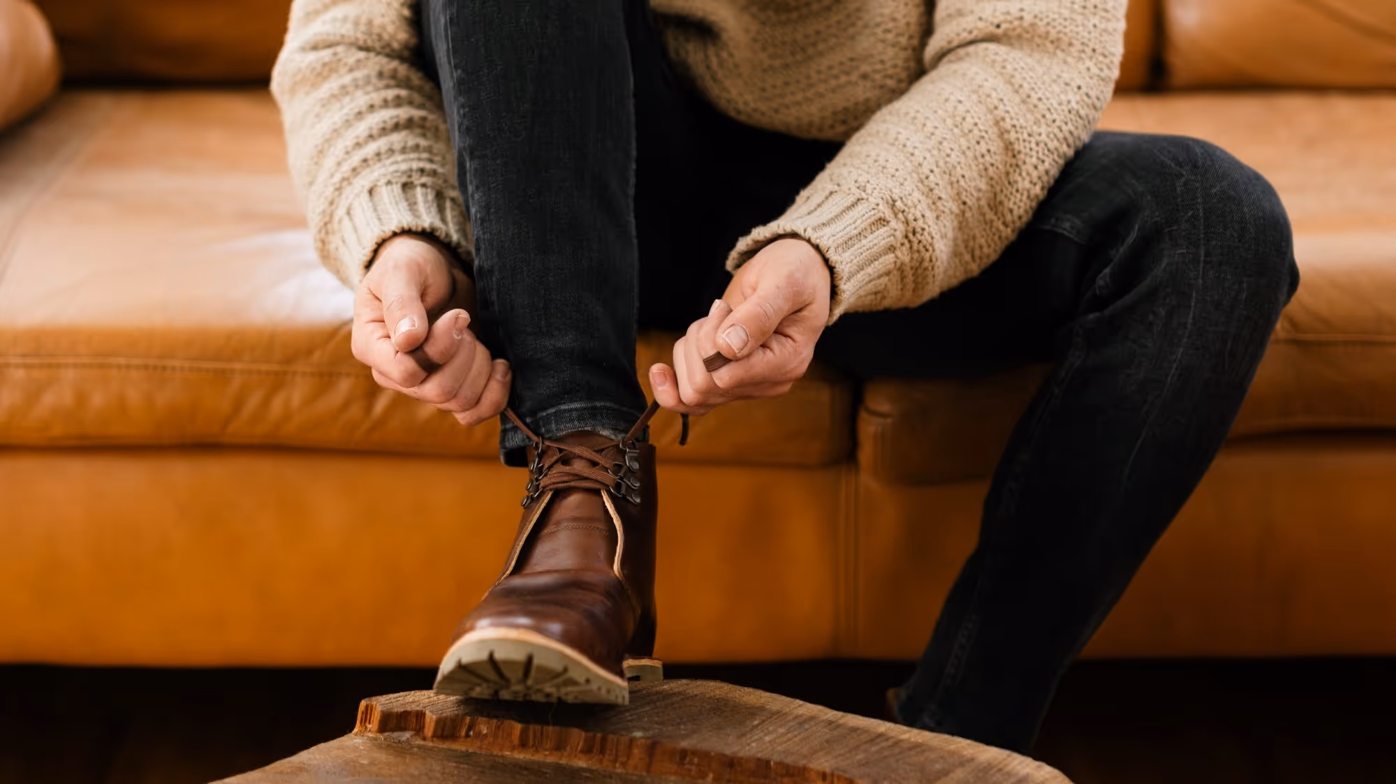 A man sitting on a couch holding his shoes.