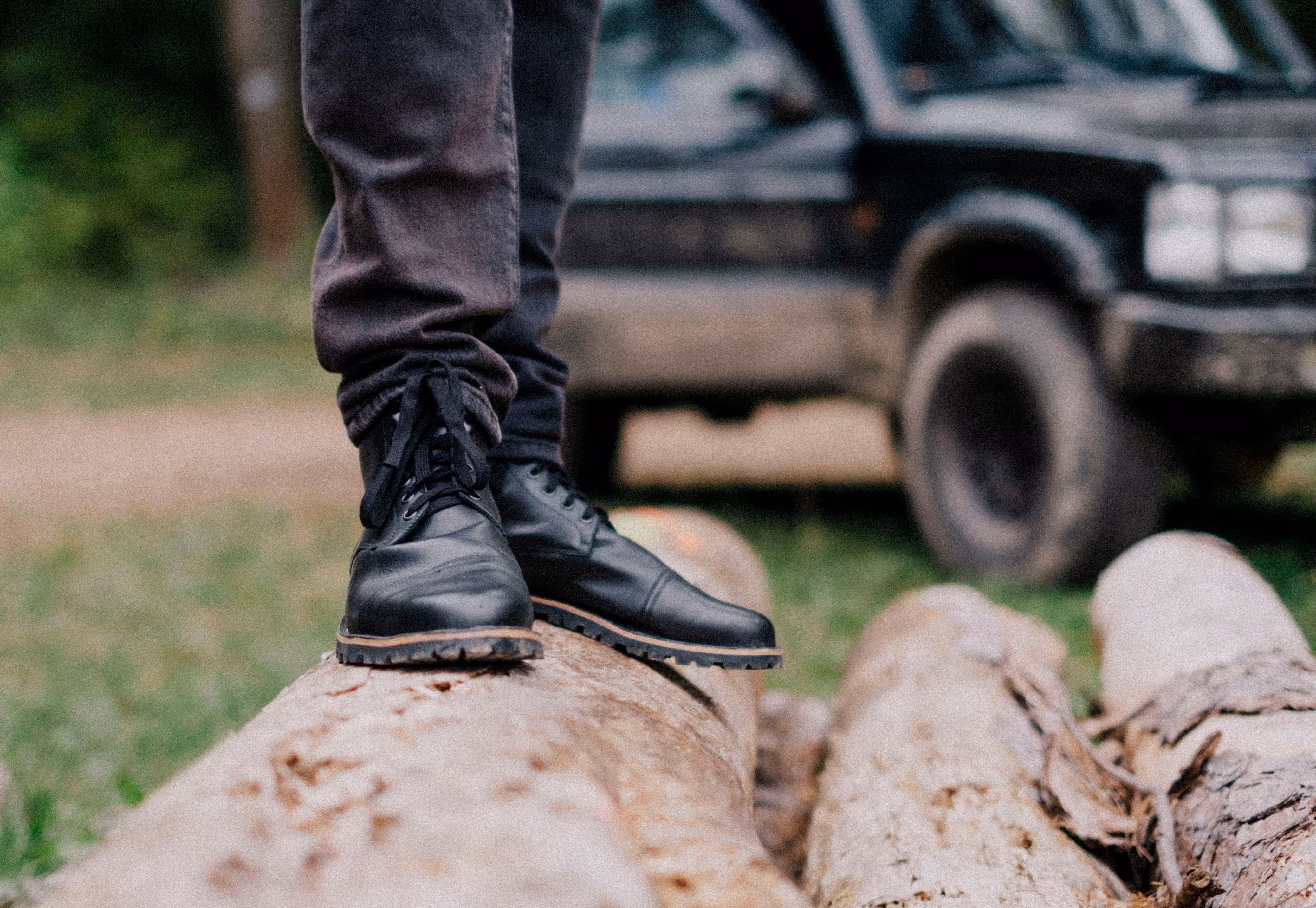 A person standing on a log in front of a truck.
