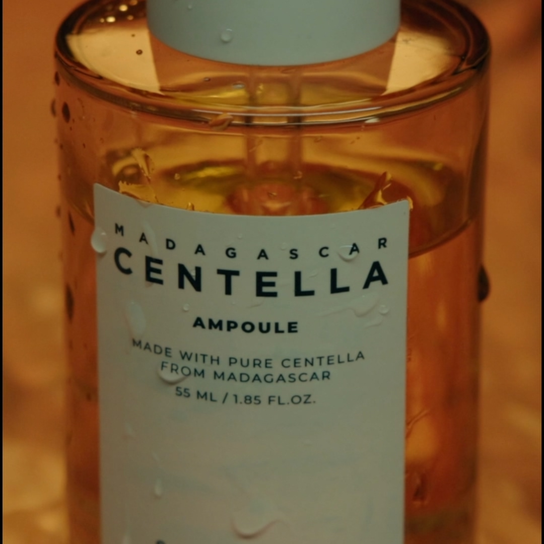 Close-up of Madagascar Centella ampoule bottle with water droplets on the surface.