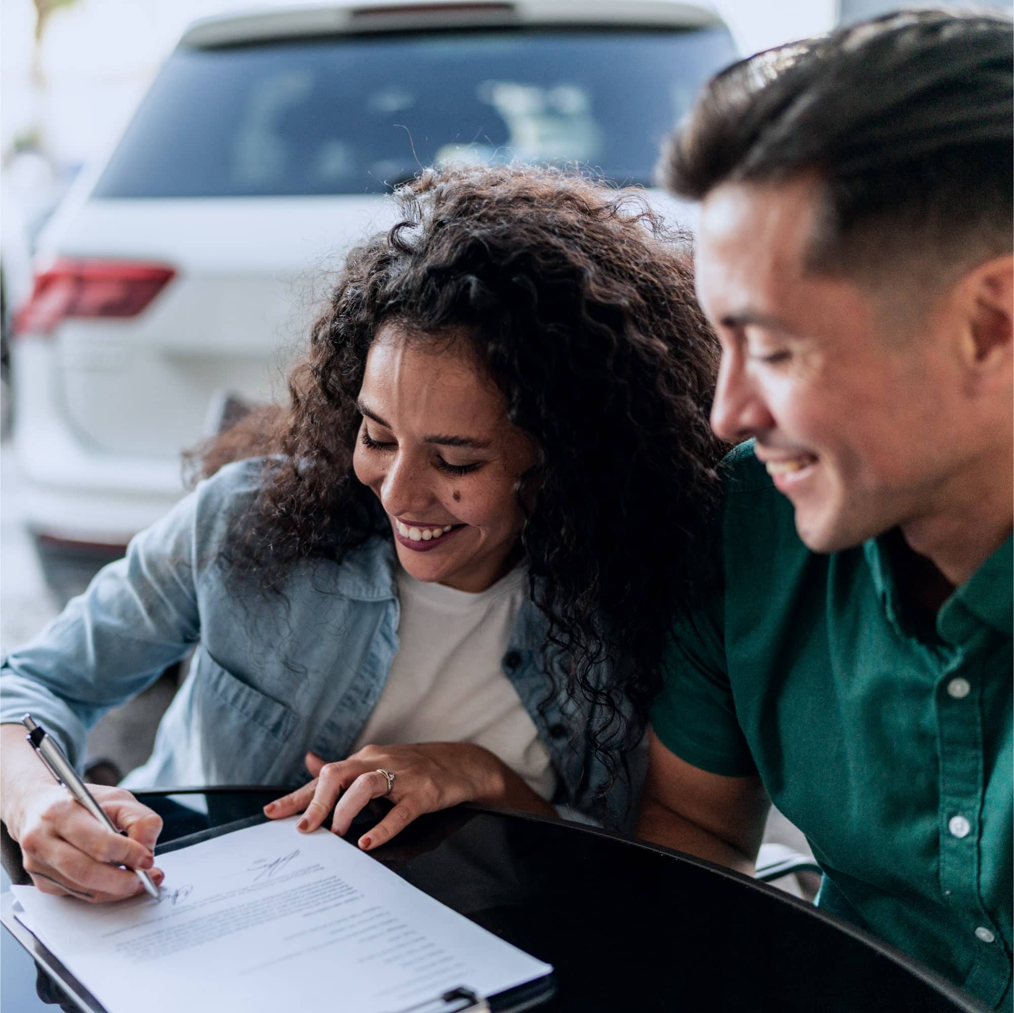 Casal preenchendo e assinando papelada referente aos documentos necessários para compra de veículo usado