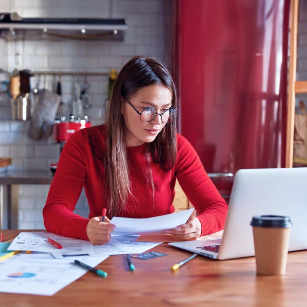 Mulher segurando o celular e sorrindo enquanto pesquisa qual é o melhor mês para dar lance em consórcio.