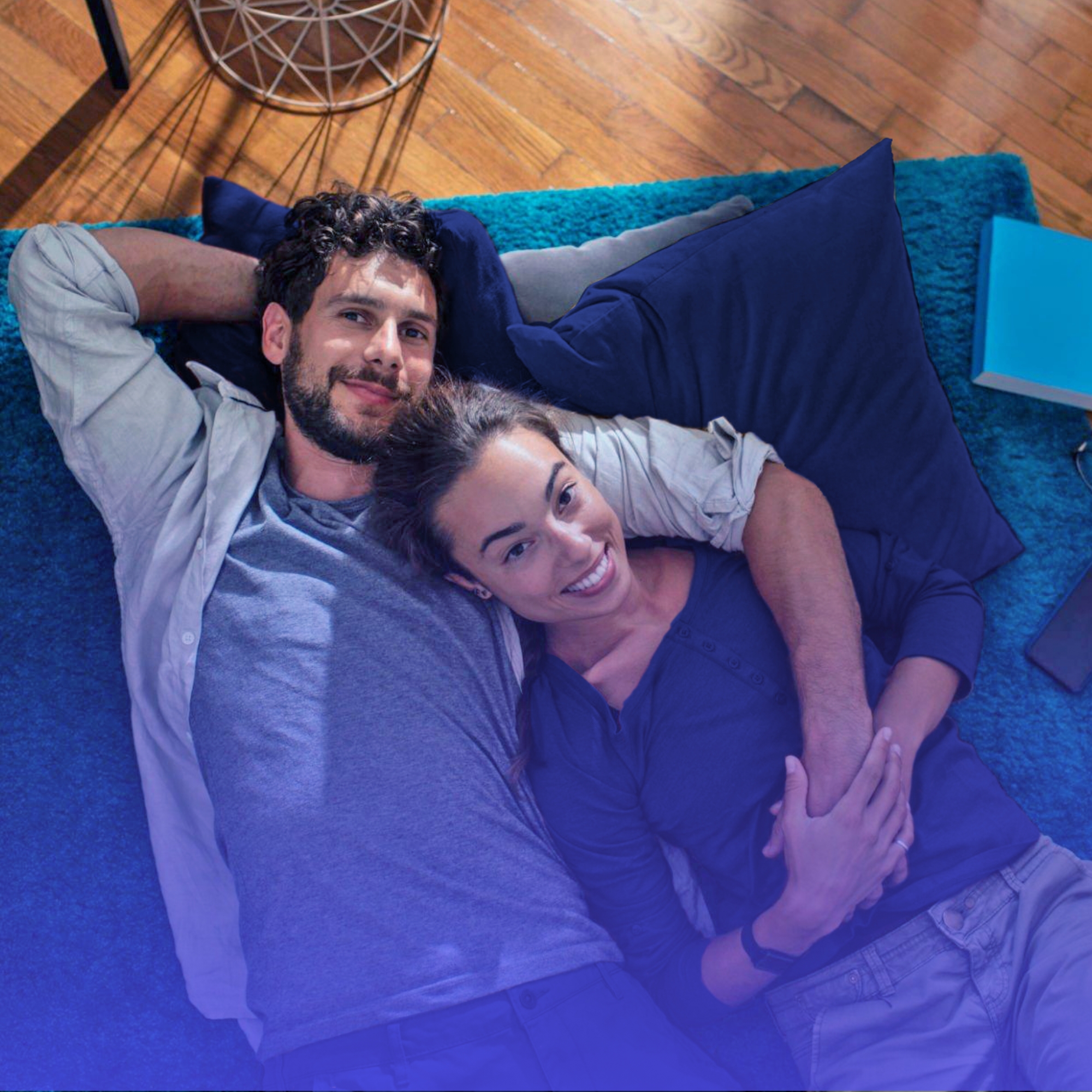 Casal sorrindo deitado no tapete após conquistar o lar próprio, representando como funciona um consórcio de imóveis.