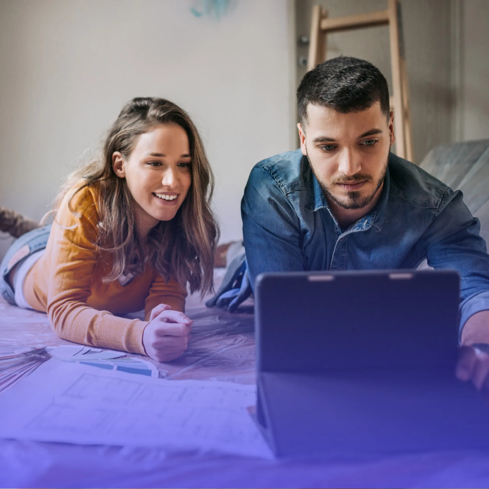 Casal planejando uma obra com notebook e plantas usando consórcio para reforma de imóvel
