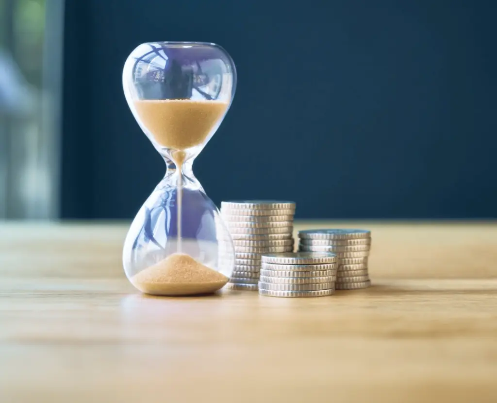 Ampulheta e moedas representando quanto tempo demora para ser contemplado no consórcio