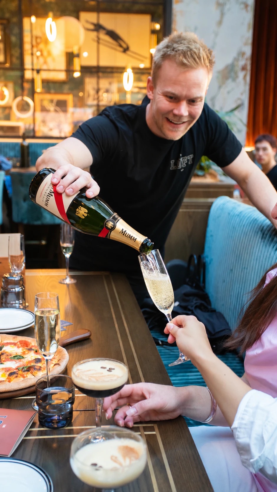 Bubbles being poured at a long lunch table at The Loft Bar