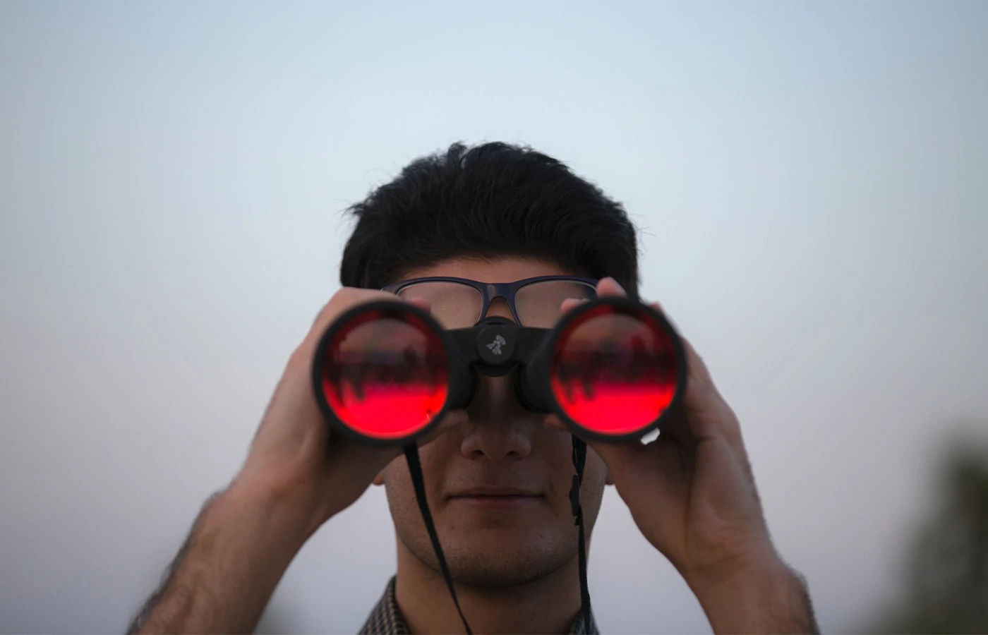Man looking through red-tinted binoculars