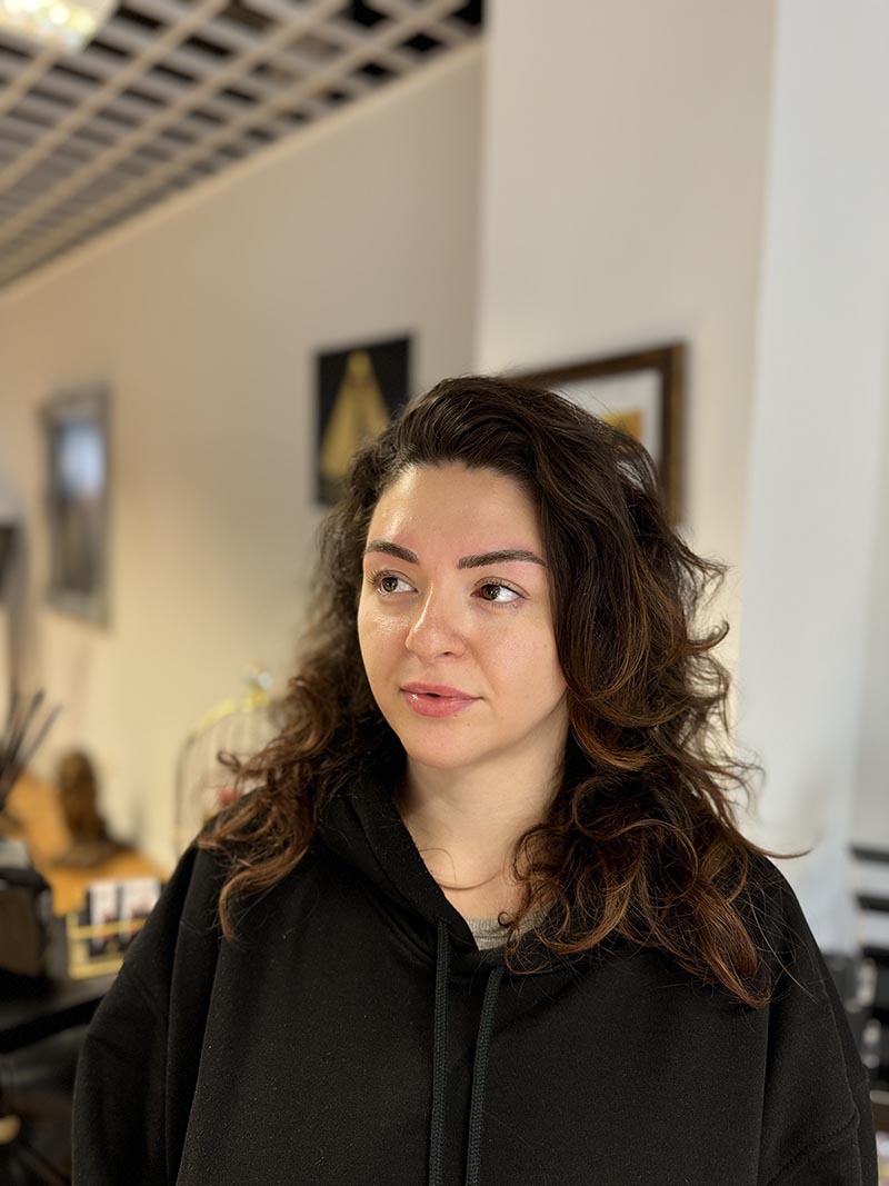 Porträt mit dunklen Locken und schwarzem Oberteil im Studio.