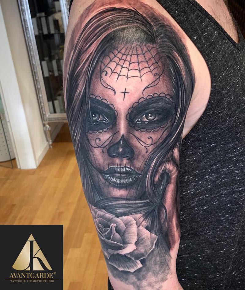 Schwarzgraues Gesichtsmotiv mit ornamentalen Linien und einer Rose am Arm.