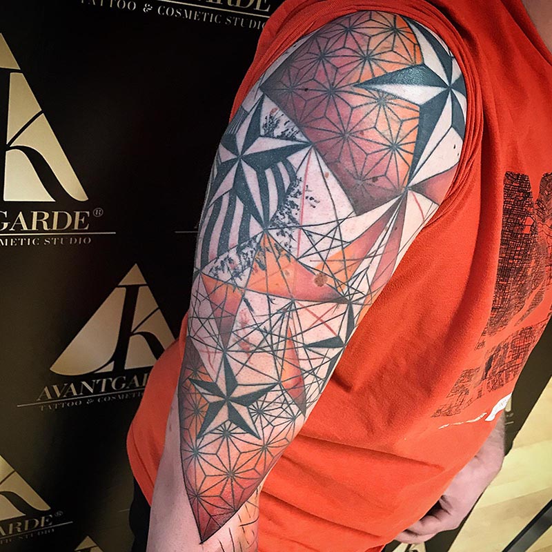 Geometrisches Oberarmtattoo mit Dreiecken und mehrfarbigen Flächen.
