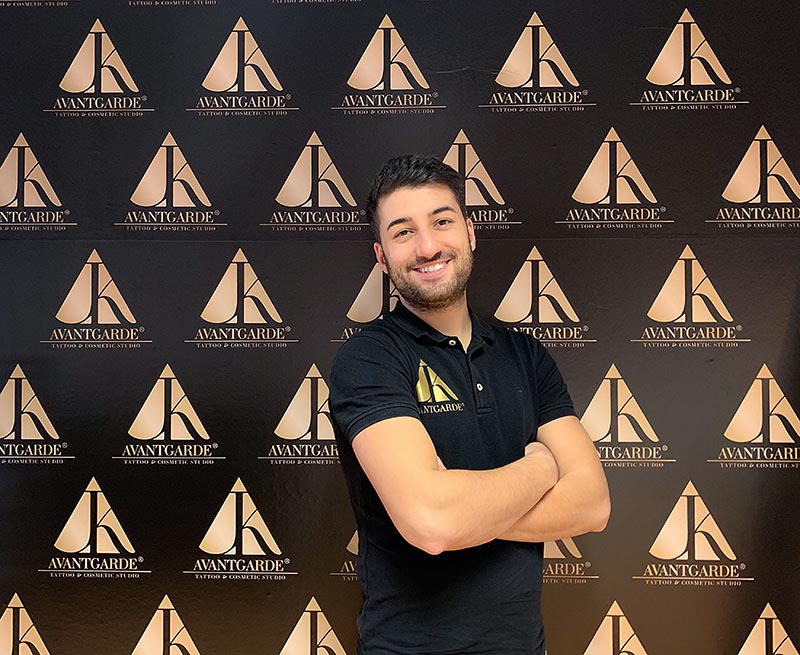 Person im schwarzen Poloshirt vor einer schwarz-goldenen Logowand.