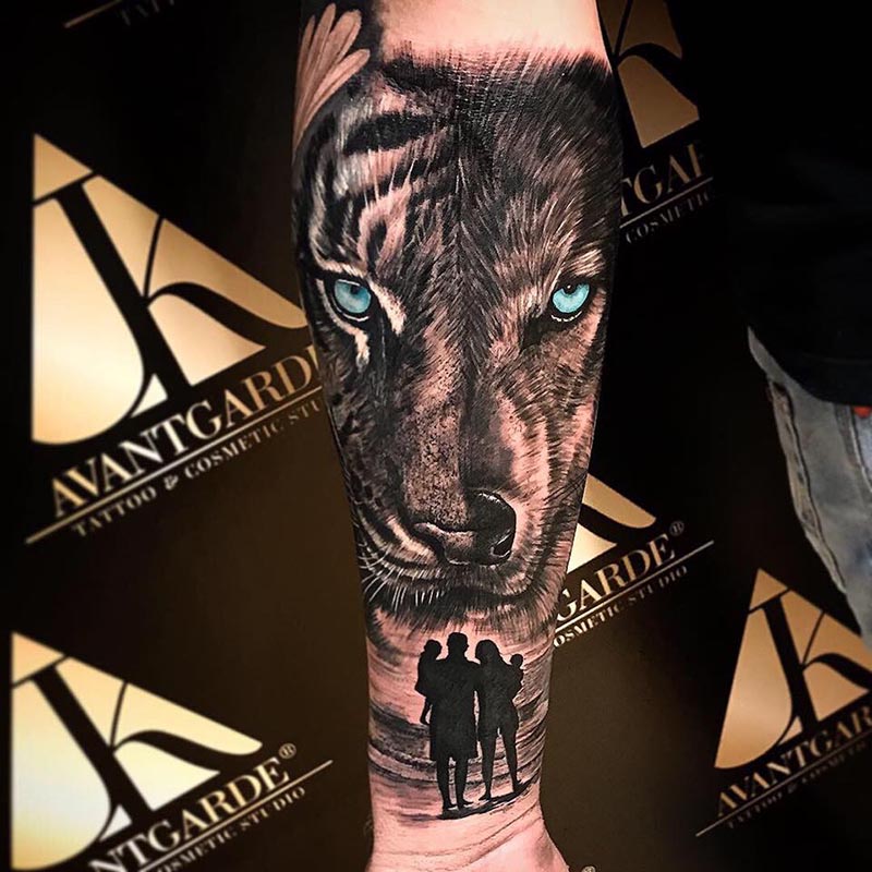 Tigerkopf mit blauen Augen und dunklen Menschensilhouetten am Unterarm.