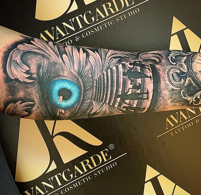 Schwarzgraues Tattoo mit einer Feder und einem leuchtend blauen Federauge.