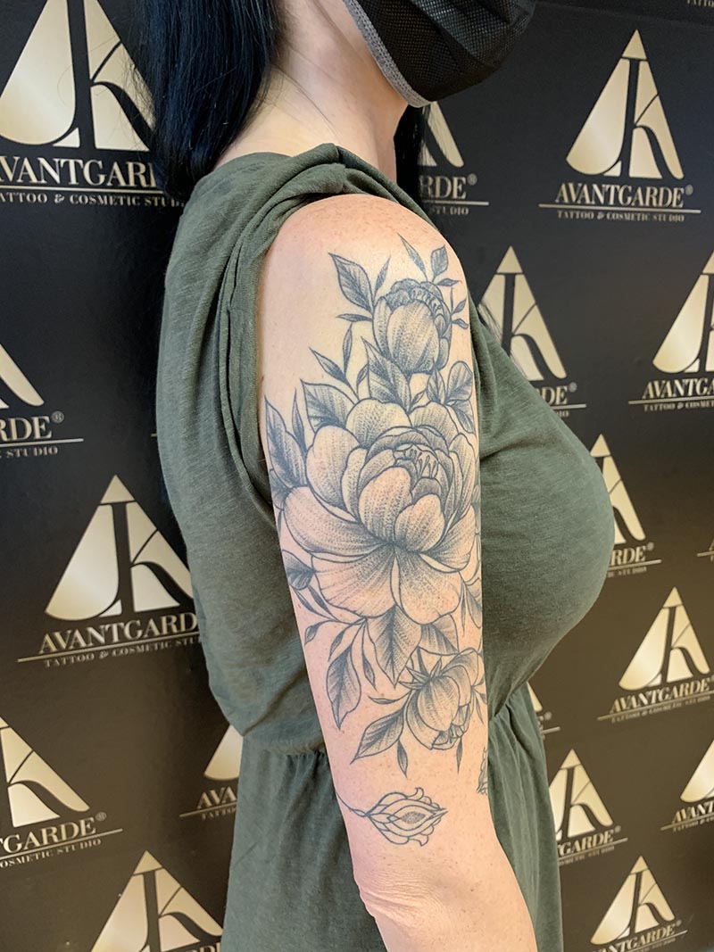 Fein gezeichnetes Blütentattoo am Oberarm.