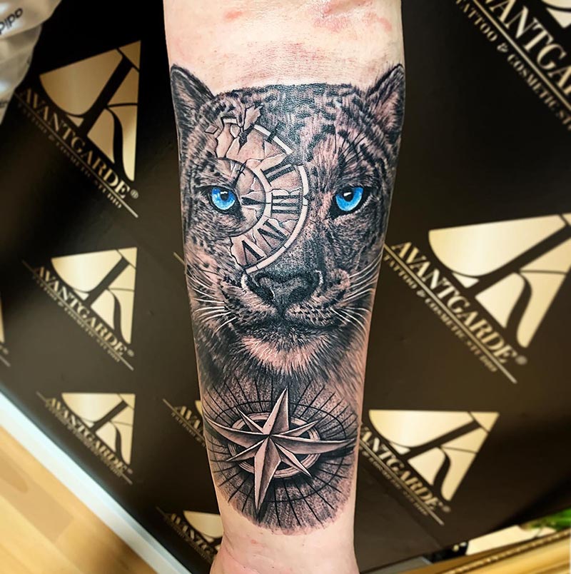 Raubkatzenkopf mit blauem Auge, runden Ornamenten und einem Sternmotiv als Tattoo.