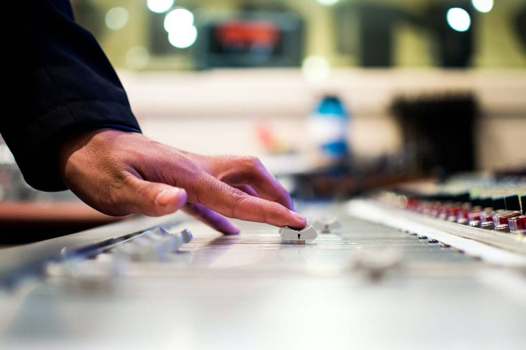 Someone adjusting the fader on an audio mixing console