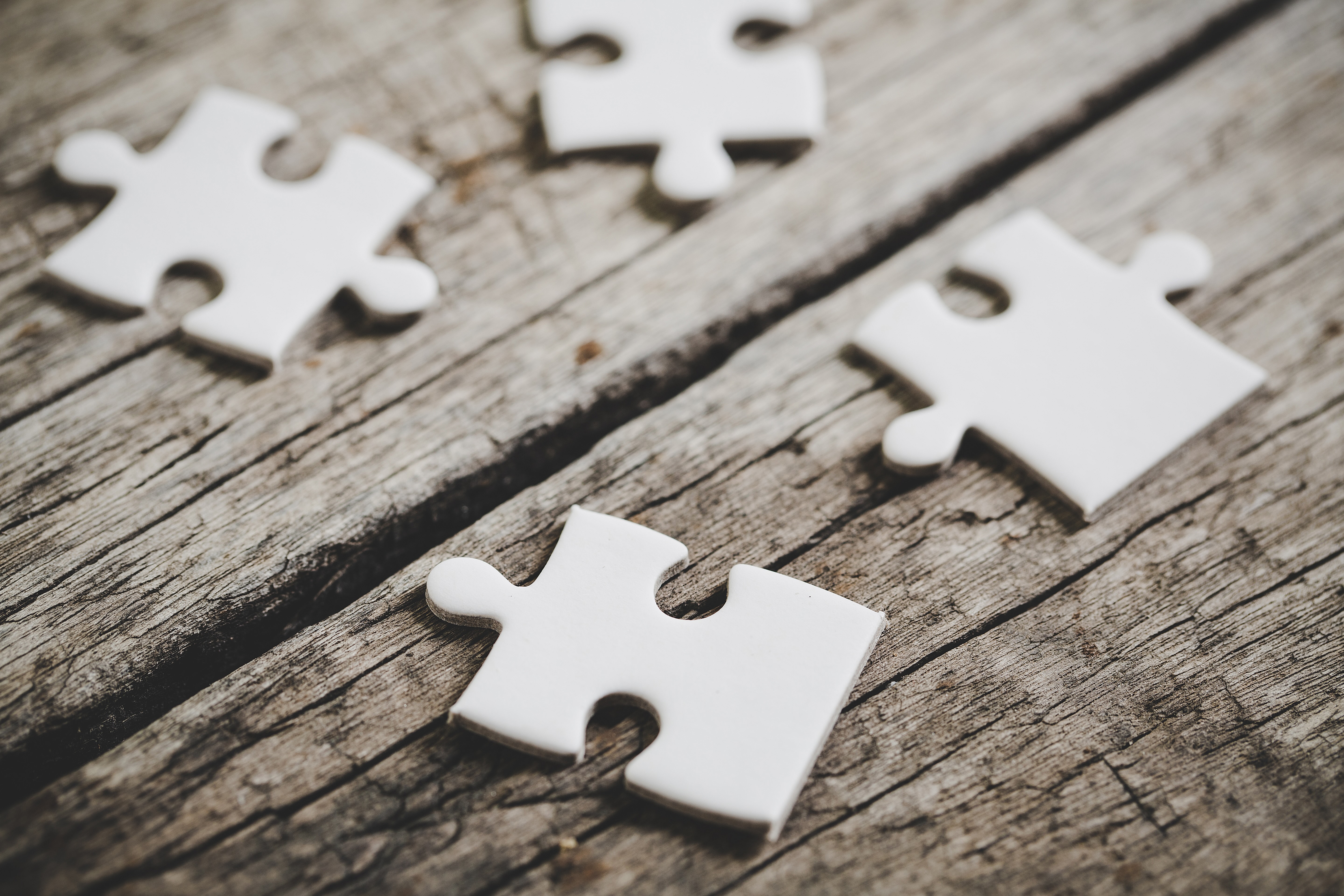 4 pièces de puzzle blanche sur une table en bois