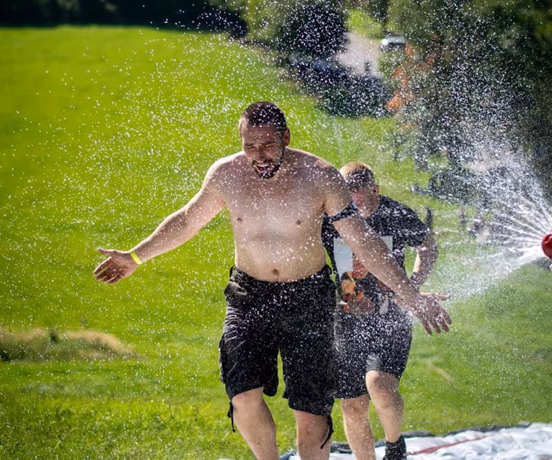 Ein Läufer genießt die Wasserdusche der Feuerwehr