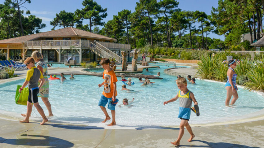 Enfants qui jouent devant une piscine dans un camping