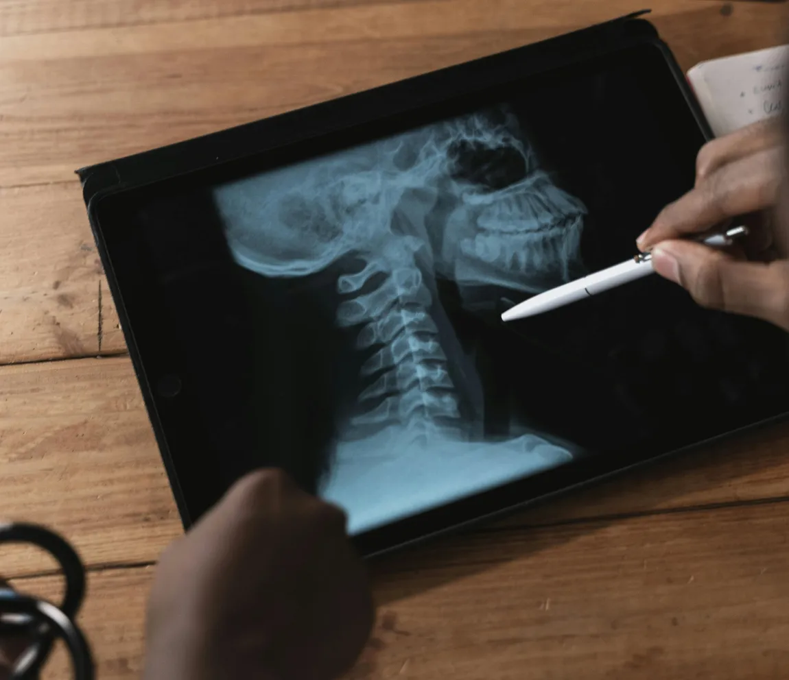 Healthcare professional analyzing cervical spine X-ray on a tablet with a stylus, illustrating Momentum's AI-driven app development for medical imaging and digital health solutions.