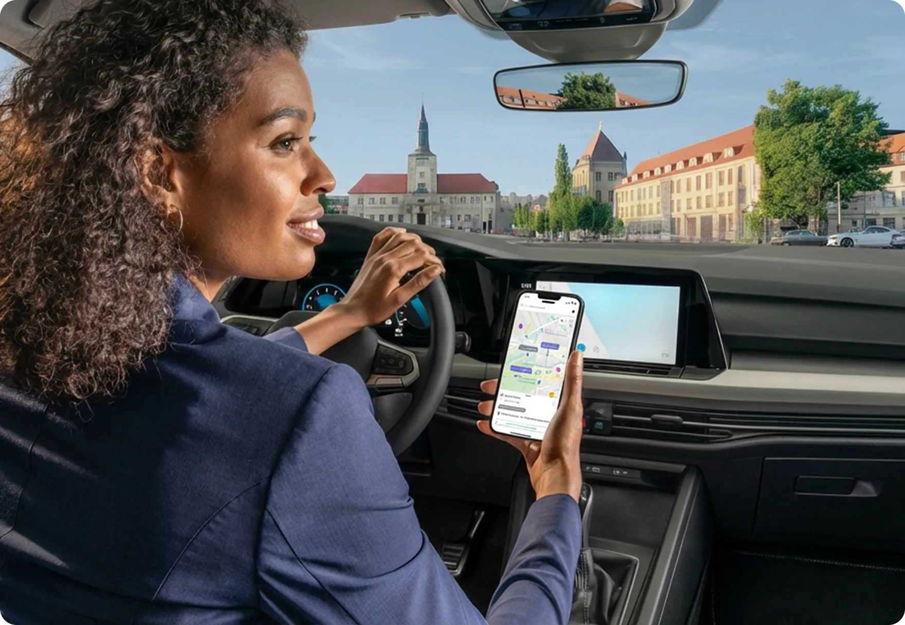 Eine Frau fährt ein Fahrzeug und hält dabei ein Smartphone, das die Vimcar-App zeigt