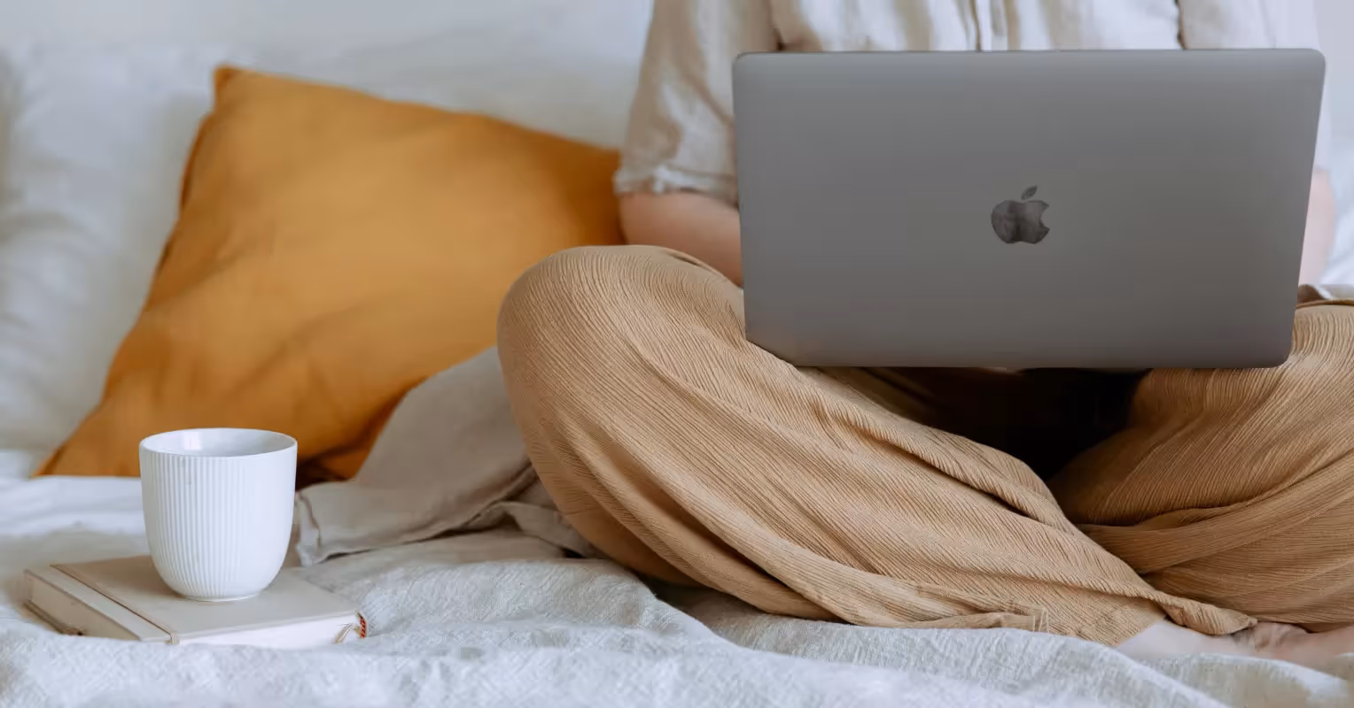 Person sitting with a laptop in their lap and a coffee cup next to them