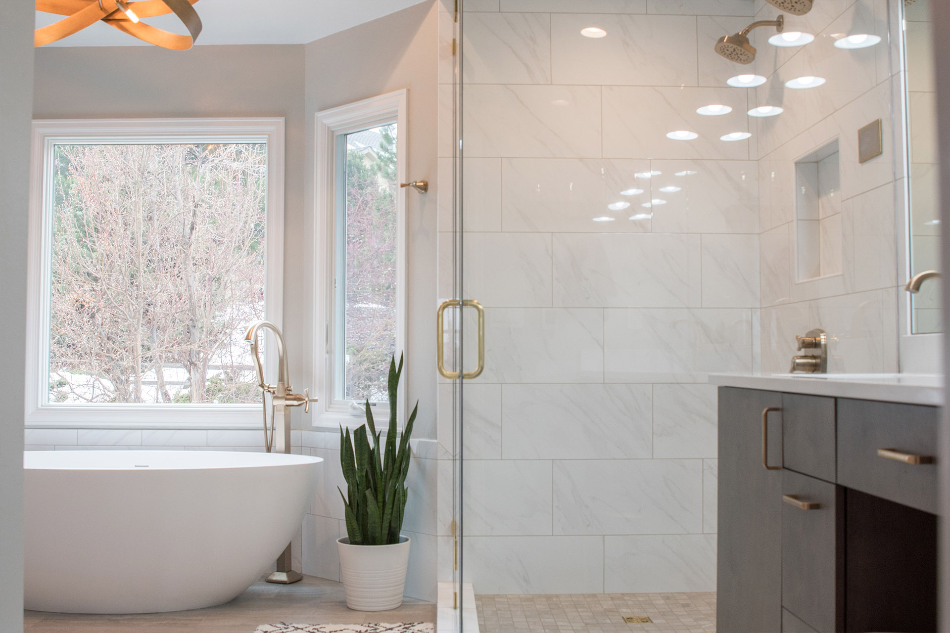 Elegant bathroom remodel in Golden, Colorado featuring a freestanding tub, warm maple cabinets, and champagne bronze fixtures by VL Builders.