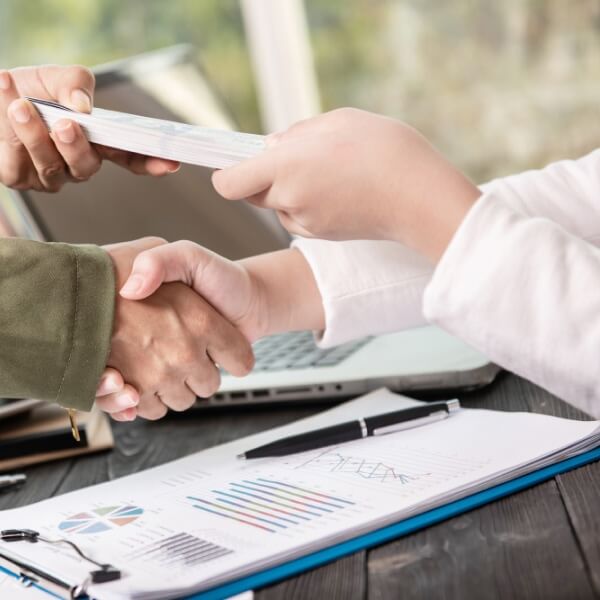 Une personne remplissant un formulaire de demande de prêt sur un ordinateur portable avec des documents financiers à côté