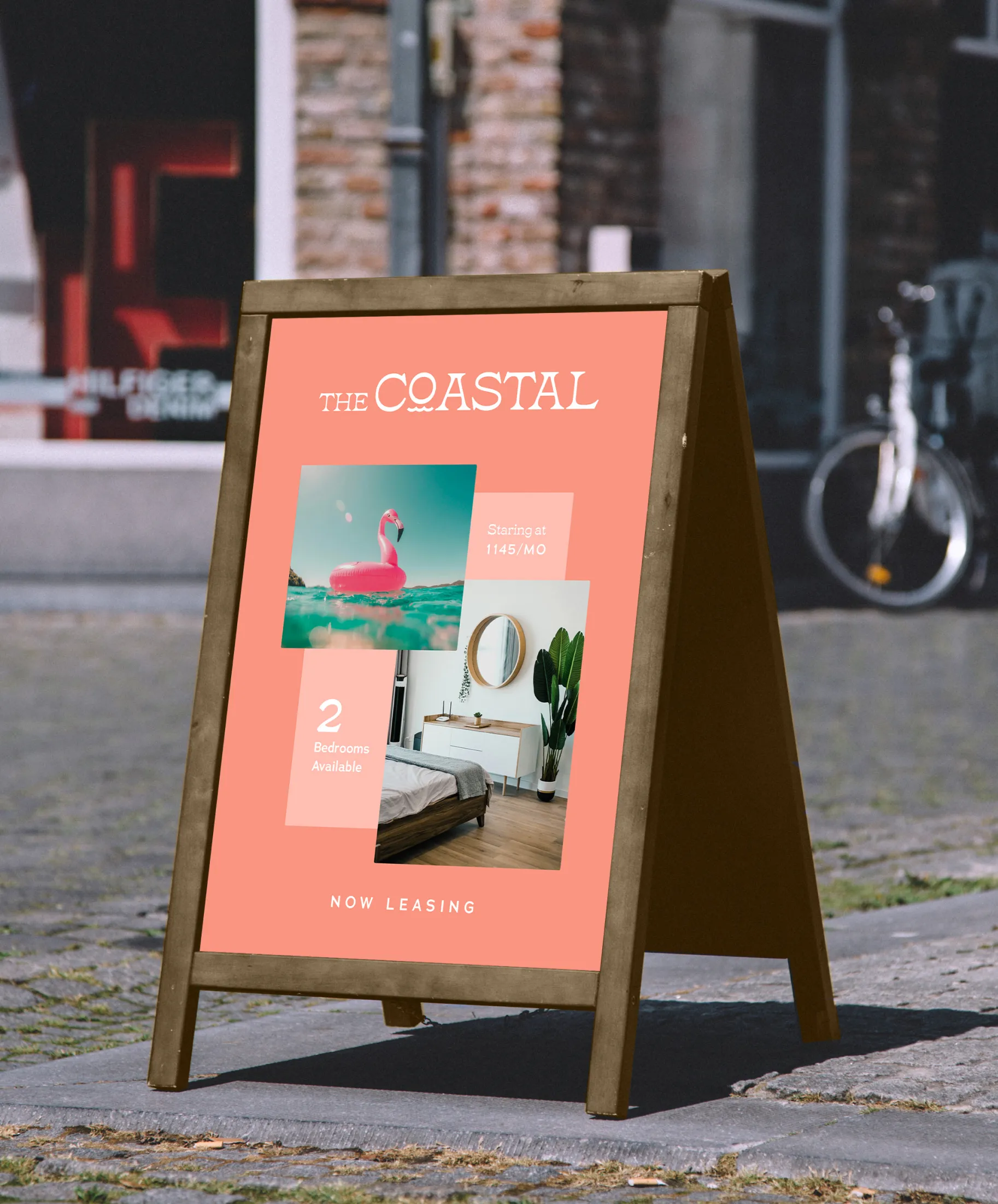 Sidewalk sign with coral background advertising The Coastal apartments, showing a pink flamingo float on water, a modern bedroom, 2 bedrooms available, and rent starting at $1145 per month.