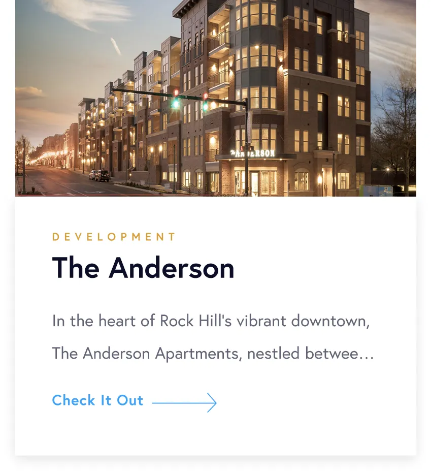 Evening view of The Anderson, a modern multi-story apartment building with lit windows and a green traffic light.