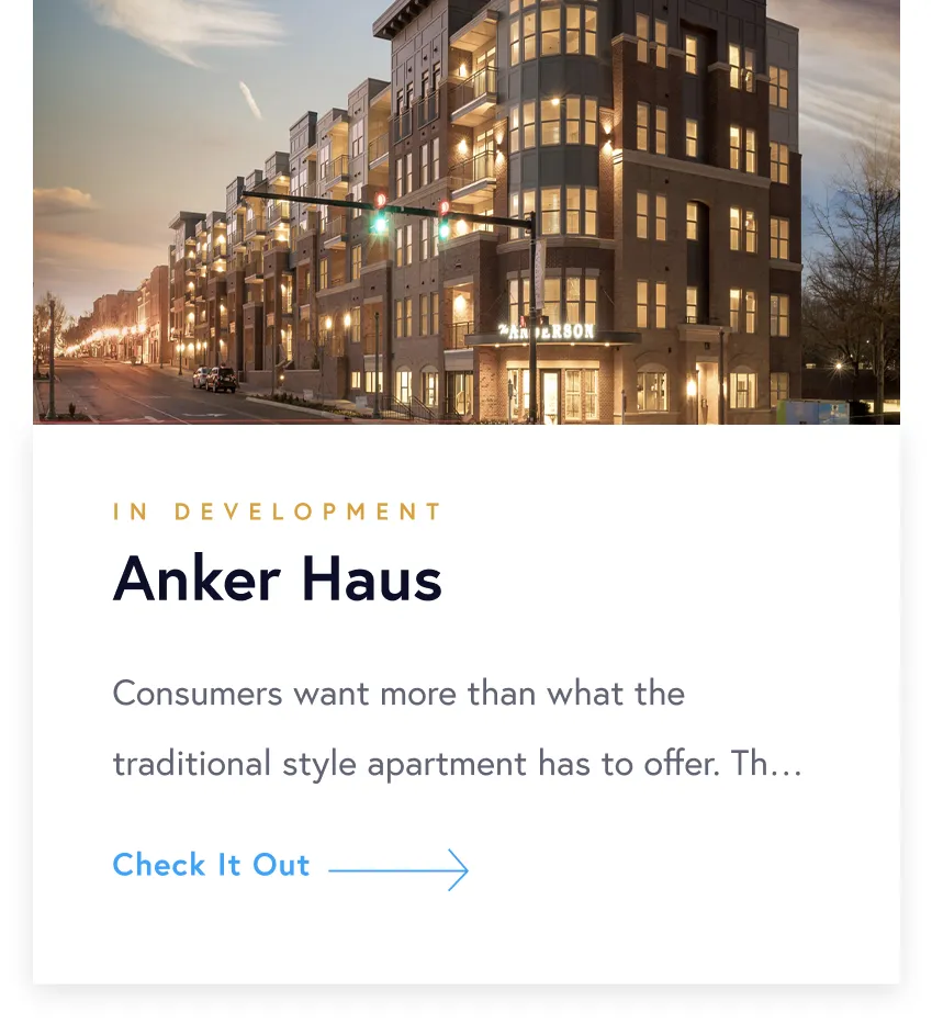 Evening view of a modern, multi-story apartment building named Anker Haus with lights glowing from windows along a street corner.