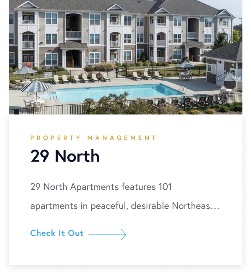 Apartment complex with a central outdoor swimming pool, lounge chairs, umbrellas, and a three-story building in the background.